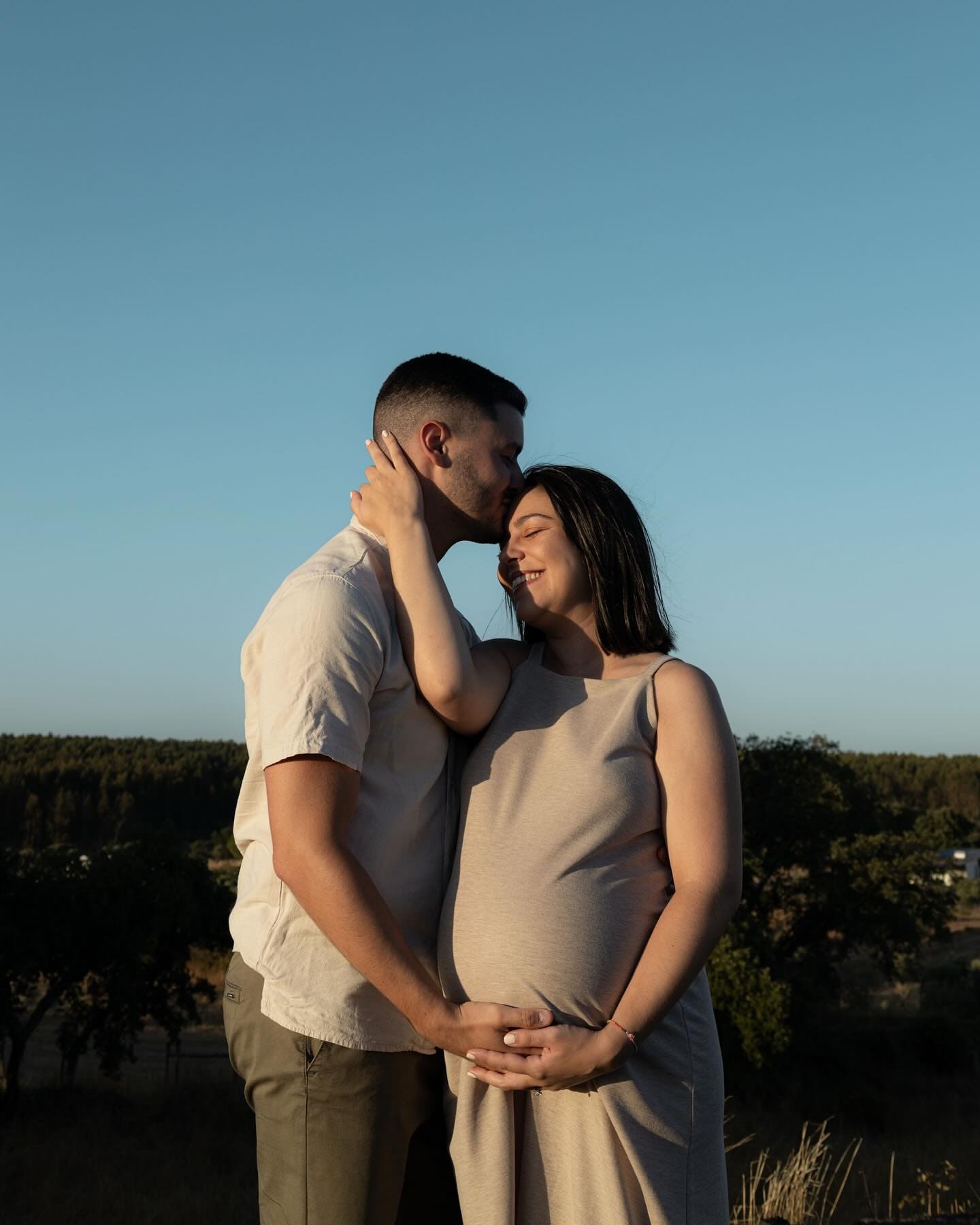 Casal à espera de bebé ao pôr do sol